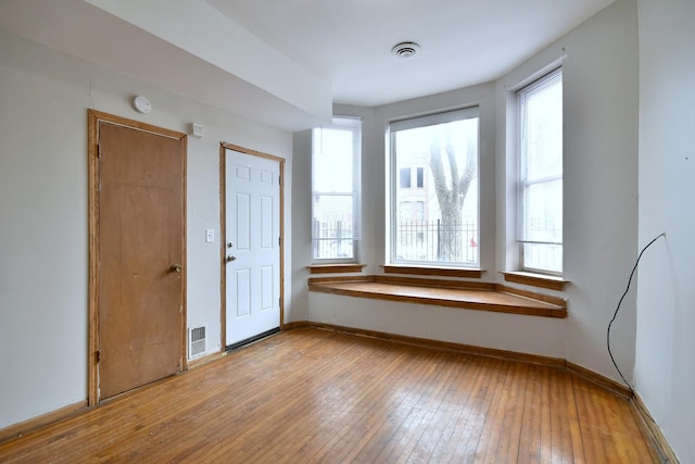 spare room featuring visible vents, hardwood / wood-style flooring, and baseboards