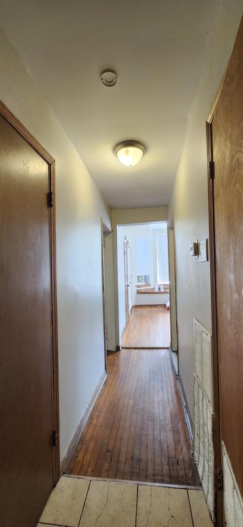 hall featuring hardwood / wood-style flooring and baseboards