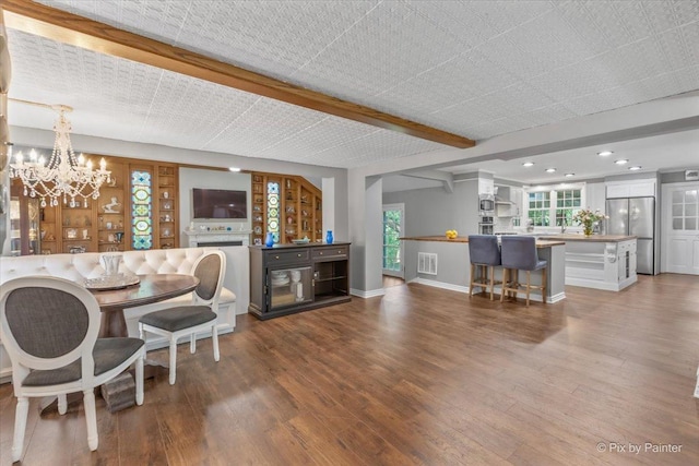 living room with beam ceiling, hardwood / wood-style floors, an inviting chandelier, and sink