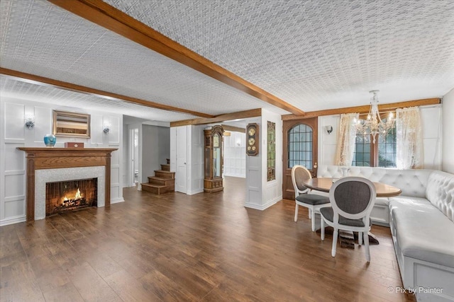 living room featuring a notable chandelier, dark hardwood / wood-style floors, and beamed ceiling