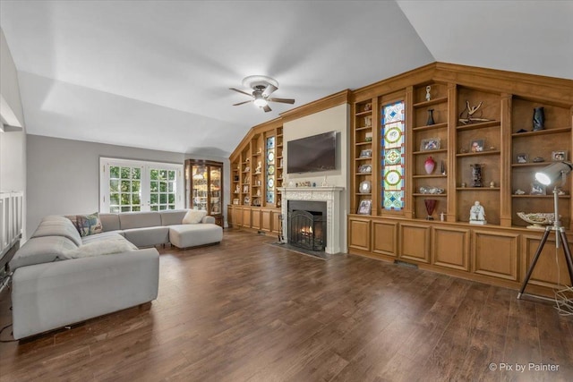 living room with ceiling fan, built in features, vaulted ceiling, and dark hardwood / wood-style floors