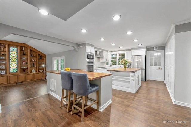 kitchen with white cabinetry, decorative backsplash, wooden counters, a kitchen island, and appliances with stainless steel finishes