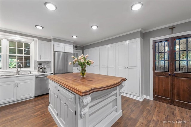 kitchen with stainless steel appliances, sink, white cabinetry, a kitchen island, and dark wood-type flooring