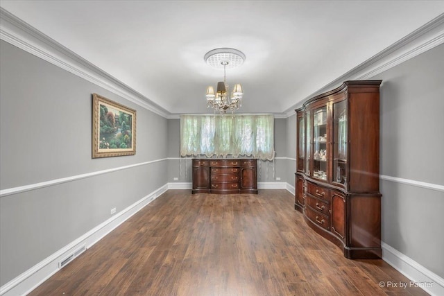 unfurnished dining area with a notable chandelier, crown molding, and dark hardwood / wood-style floors