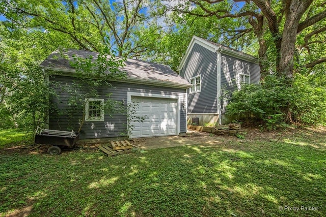 back of house featuring a lawn, a garage, and an outdoor structure