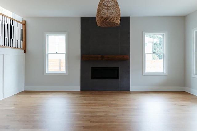 unfurnished living room with a tile fireplace and light hardwood / wood-style flooring