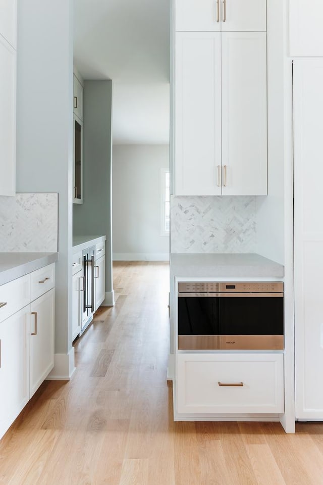 kitchen featuring white cabinets, oven, and light hardwood / wood-style flooring