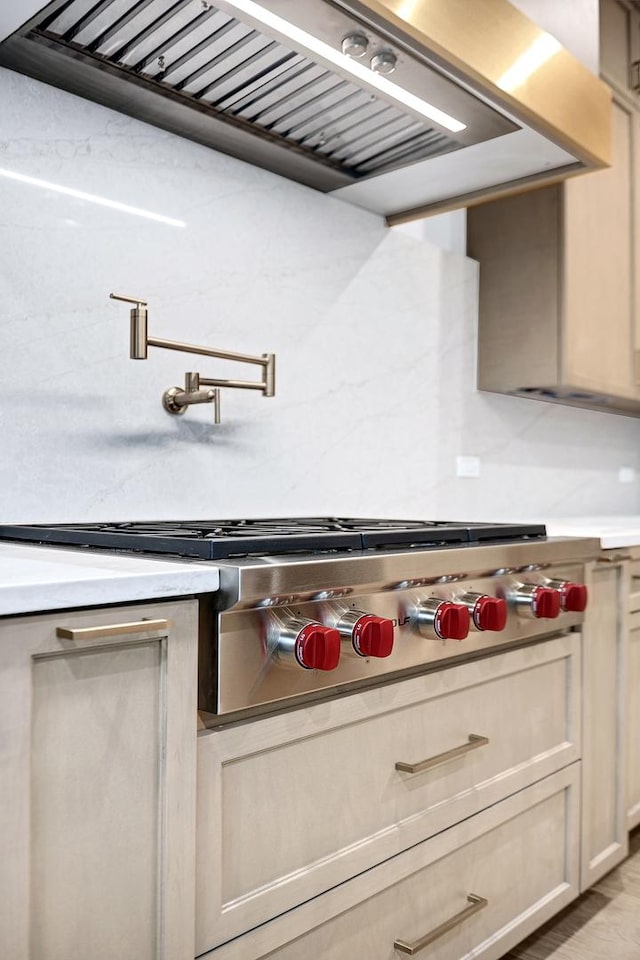 kitchen with cream cabinets, stainless steel gas stovetop, and range hood