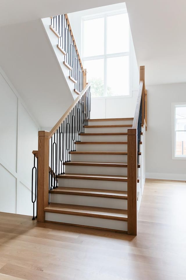 stairway featuring a healthy amount of sunlight and wood-type flooring