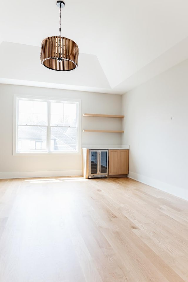 unfurnished living room featuring light hardwood / wood-style floors and a raised ceiling