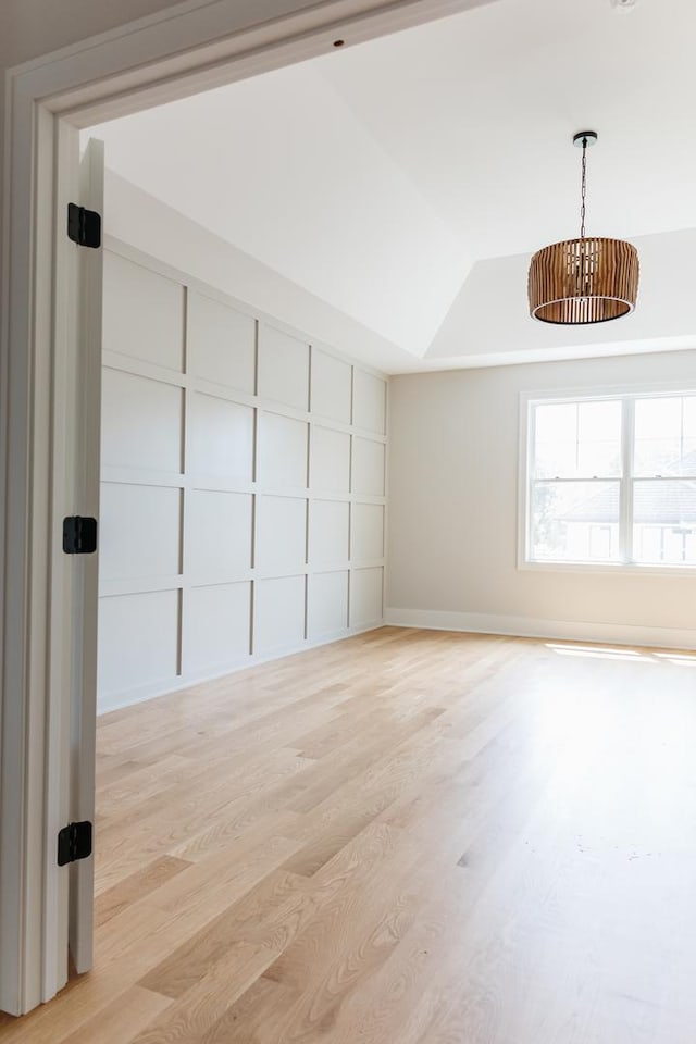 spare room featuring light hardwood / wood-style floors and a raised ceiling