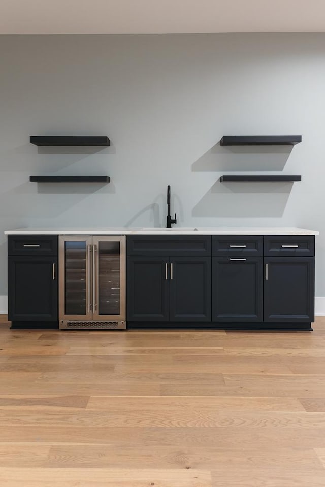 bar featuring wine cooler, sink, and light hardwood / wood-style floors