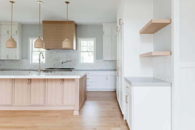 kitchen featuring white cabinetry, sink, light hardwood / wood-style flooring, backsplash, and pendant lighting