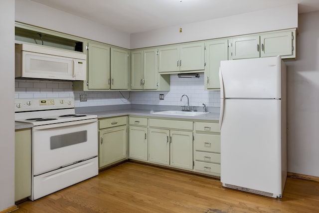 kitchen with sink, white appliances, light hardwood / wood-style flooring, backsplash, and green cabinets