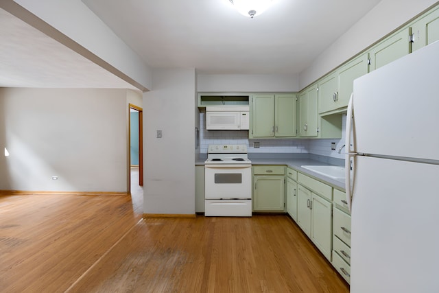 kitchen with sink, white appliances, green cabinetry, backsplash, and light wood-type flooring