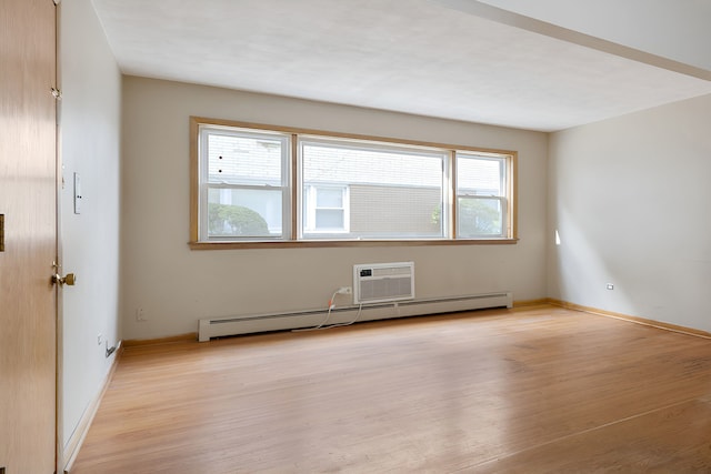 empty room featuring an AC wall unit, light wood-type flooring, and baseboard heating