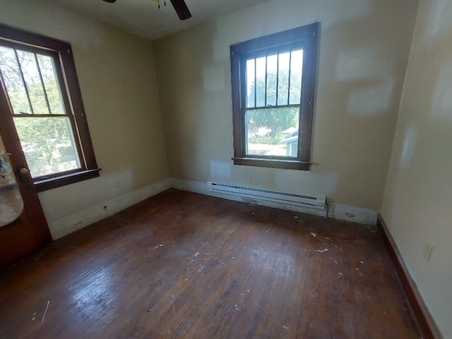 empty room featuring ceiling fan, baseboard heating, plenty of natural light, and dark hardwood / wood-style floors