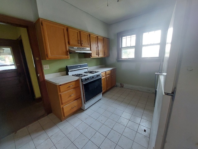 kitchen featuring light tile patterned floors, gas range gas stove, and a wealth of natural light