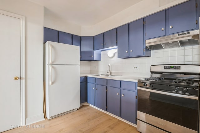 kitchen featuring white refrigerator, decorative backsplash, light wood-type flooring, blue cabinetry, and stainless steel range with gas stovetop