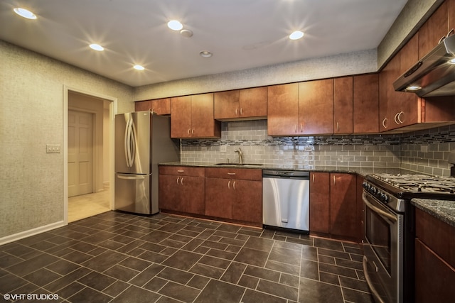 kitchen featuring appliances with stainless steel finishes, dark stone counters, decorative backsplash, and sink