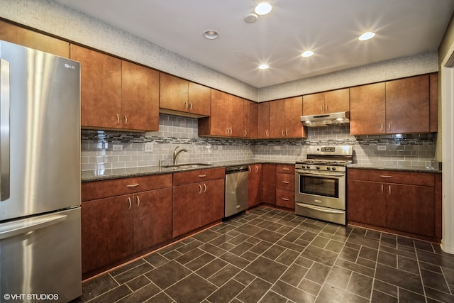 kitchen with appliances with stainless steel finishes, dark stone counters, sink, and backsplash