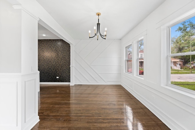 unfurnished dining area with a notable chandelier and dark hardwood / wood-style floors