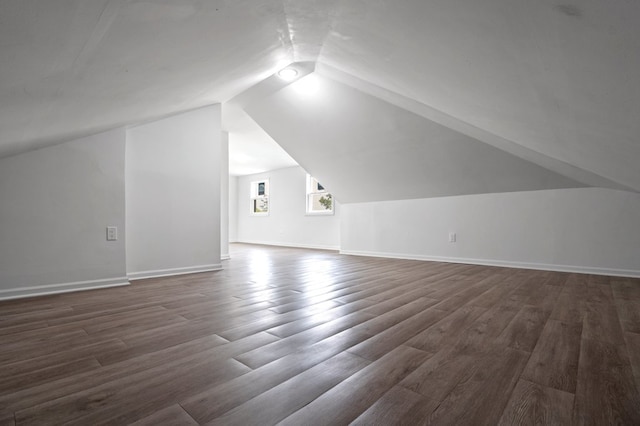 bonus room with vaulted ceiling and dark wood-type flooring