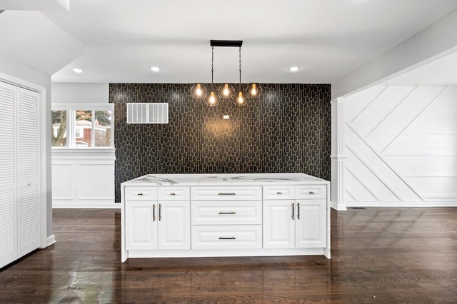 interior space with white cabinets, light stone counters, decorative light fixtures, and dark hardwood / wood-style flooring