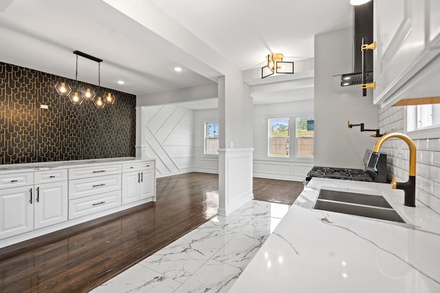 kitchen featuring light stone counters, white cabinets, hanging light fixtures, sink, and dark hardwood / wood-style floors