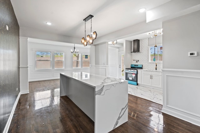 kitchen with white cabinets, stainless steel gas stove, dark hardwood / wood-style floors, and wall chimney range hood