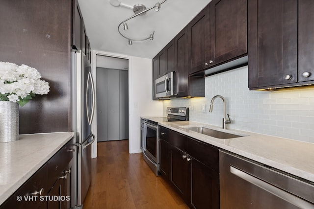 kitchen with sink, tasteful backsplash, dark brown cabinets, dark wood-type flooring, and stainless steel appliances