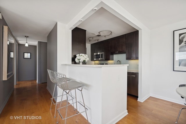 kitchen with kitchen peninsula, light hardwood / wood-style floors, stainless steel appliances, and tasteful backsplash