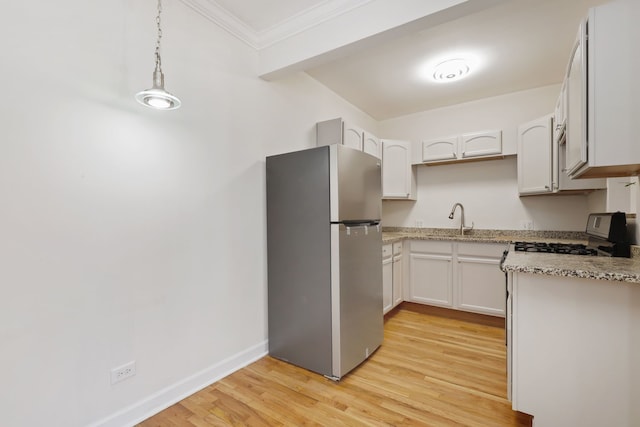 kitchen with pendant lighting, stove, stainless steel fridge, white cabinetry, and light hardwood / wood-style floors