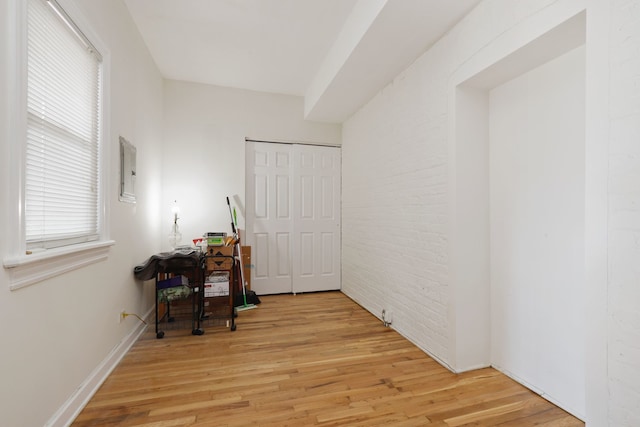 home office with brick wall and light hardwood / wood-style floors