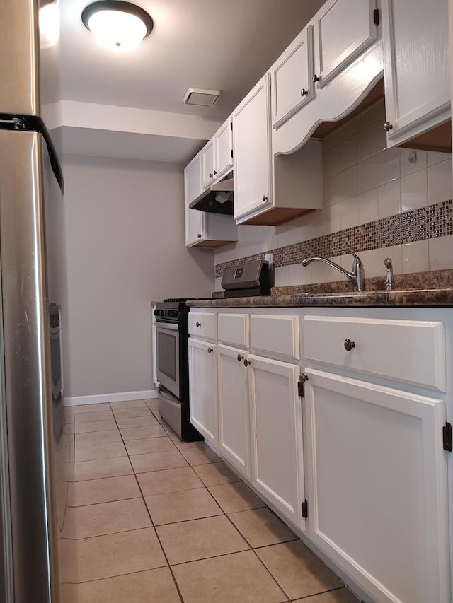 kitchen with appliances with stainless steel finishes, tasteful backsplash, sink, light tile patterned floors, and white cabinets