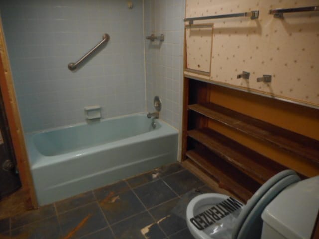 bathroom with toilet, tile patterned floors, and tiled shower / bath