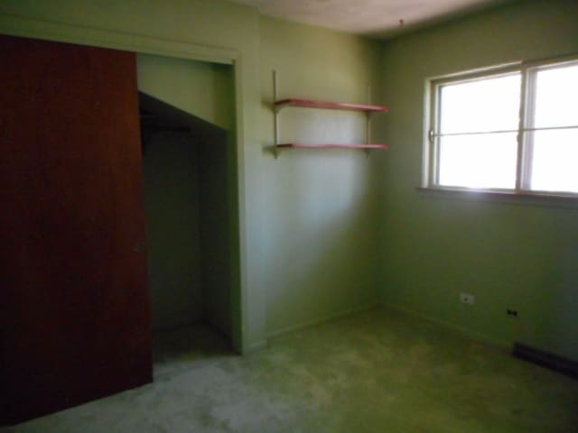 unfurnished bedroom featuring light carpet and a closet