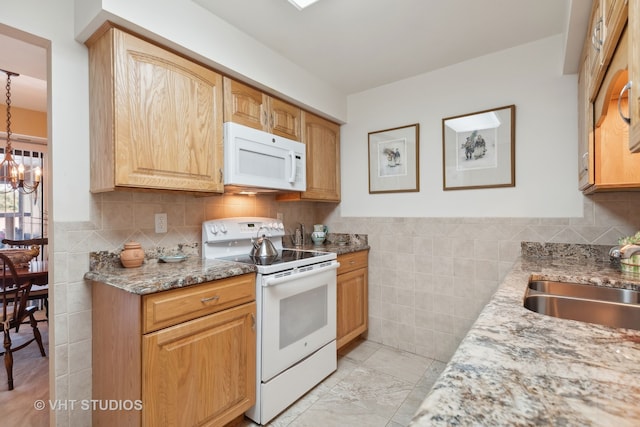 kitchen featuring white appliances, sink, pendant lighting, light stone counters, and an inviting chandelier