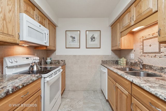 kitchen with tile walls, sink, light stone countertops, and white appliances