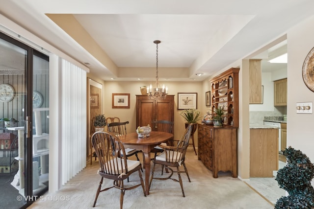 carpeted dining area with a notable chandelier and a tray ceiling