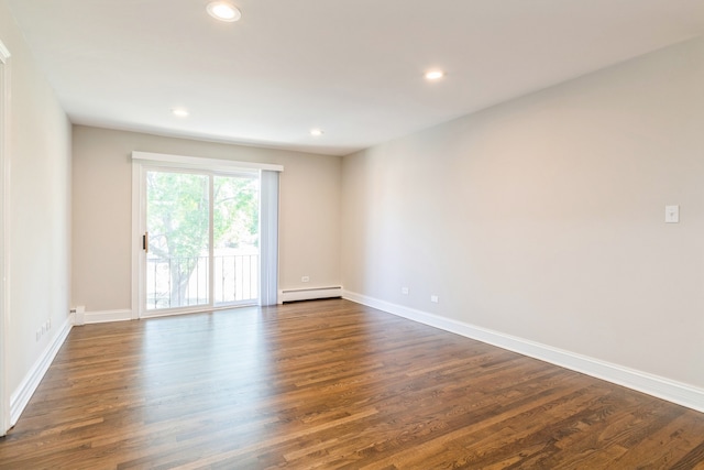 spare room with a baseboard heating unit and dark hardwood / wood-style floors