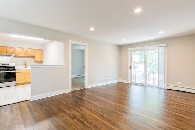 unfurnished living room featuring light hardwood / wood-style floors and a baseboard heating unit