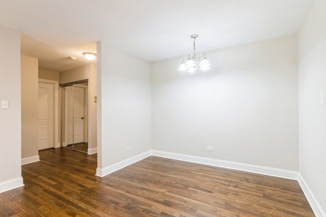 spare room with a notable chandelier and dark hardwood / wood-style flooring