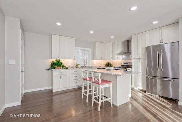 kitchen with stainless steel appliances, wall chimney range hood, dark hardwood / wood-style floors, and white cabinets