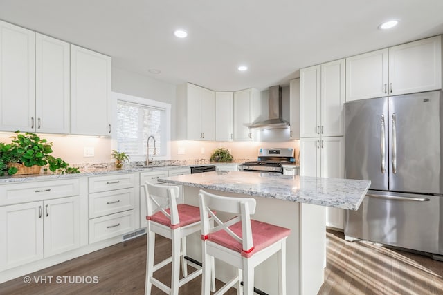 kitchen featuring stainless steel appliances, wall chimney exhaust hood, dark hardwood / wood-style floors, and white cabinets