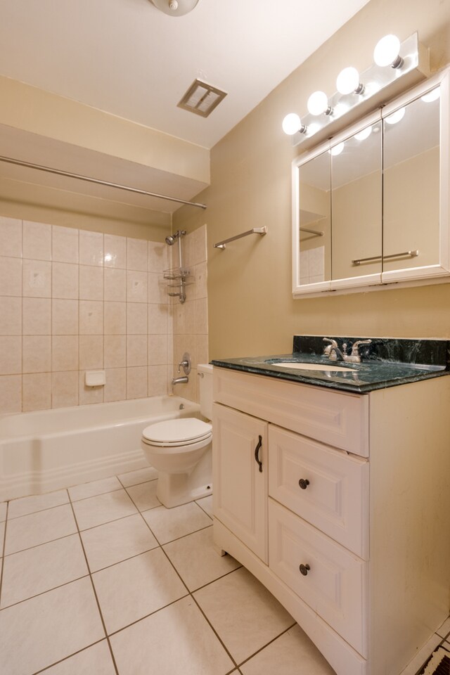 full bathroom featuring tile patterned floors, tiled shower / bath combo, vanity, and toilet