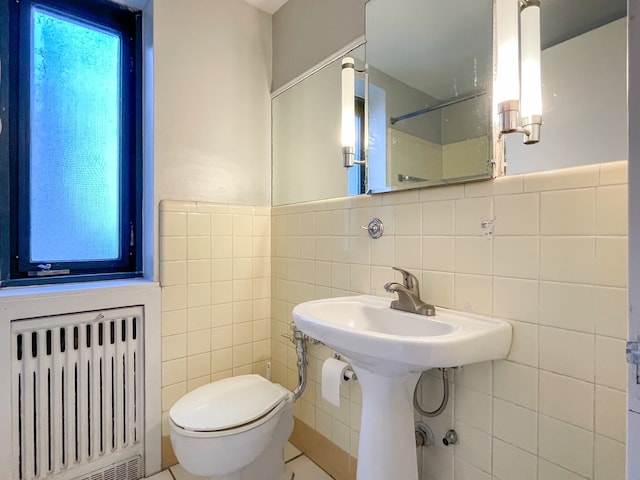 bathroom featuring tile patterned floors, radiator, tile walls, and toilet