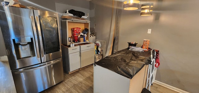 kitchen with white cabinetry, light wood-type flooring, and stainless steel fridge