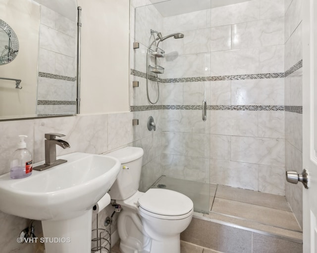 bathroom with tile walls, toilet, and a shower with door