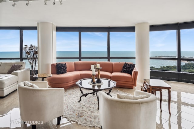 tiled living room featuring floor to ceiling windows, plenty of natural light, and a water view